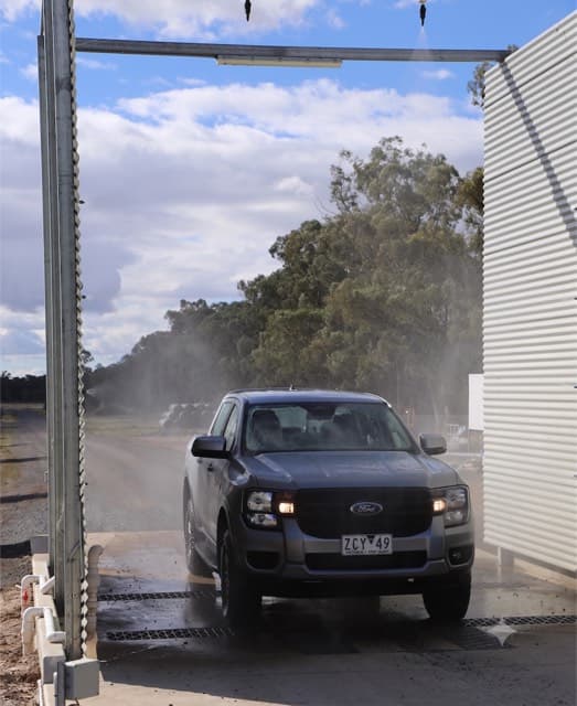Vehicle passing through a farm-gate wheel and body wash station